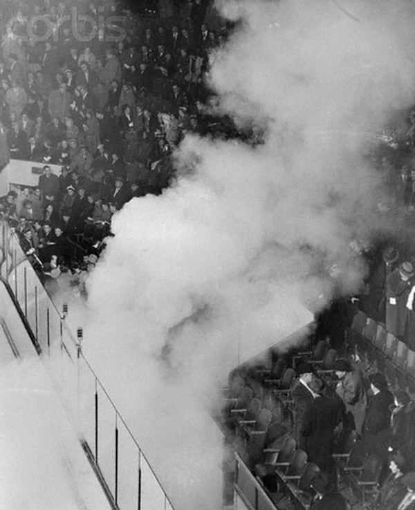 17 Mar 1955, Montreal, Canada --- Smoke rising from a tear gas bomb drifts through the Forum arena March 17 as 15, 000 demonstrators angrily protest the suspension of Maurice "The Rocket" Richard by National Hockey League President Clarence Campbell. The bomb was set off by a demonstrator at the intermission between the first and second periods. It was at this point that Fire Chief Armand Pare ordered the game halted for the "protection of the people." Montreal trailed at the time, 4-1, and that was declared the final score. The calm of the spectators in the upper seats, which were unaffected by the bomb's fumes, prevented crushing at the exits. --- Image by © Bettmann/CORBIS
